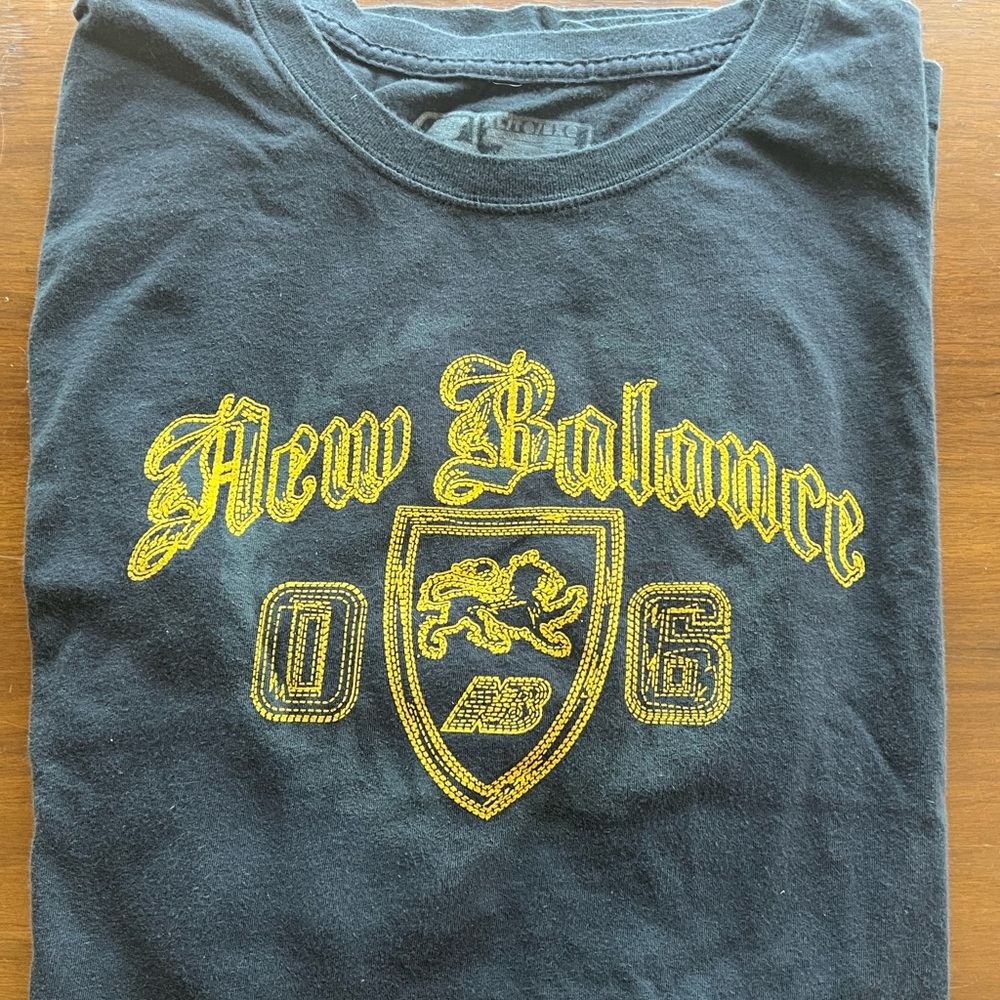 New Balance Black Tee with Yellow Crest Design